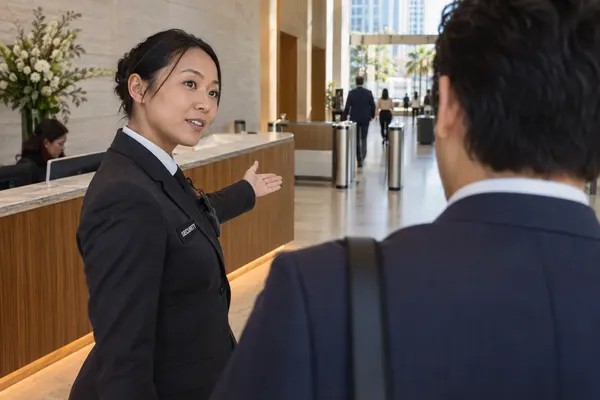 Illustrative private security work in Los Angeles, California: Asian woman guiding a visitor at modern business reception
