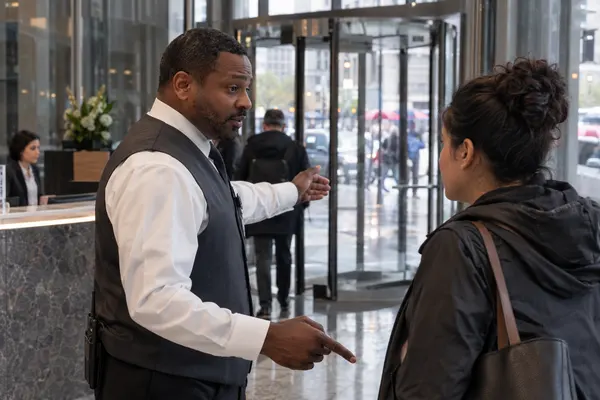 Illustrative private security work in Chicago, Illinois: Black male officer assisting office visitor at revolving-door lobby