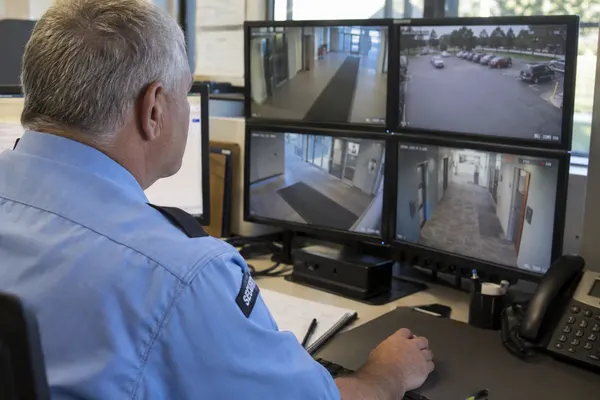 Illustrative private security work in Des Moines, Iowa: Mature male officer monitoring insurance-campus CCTV