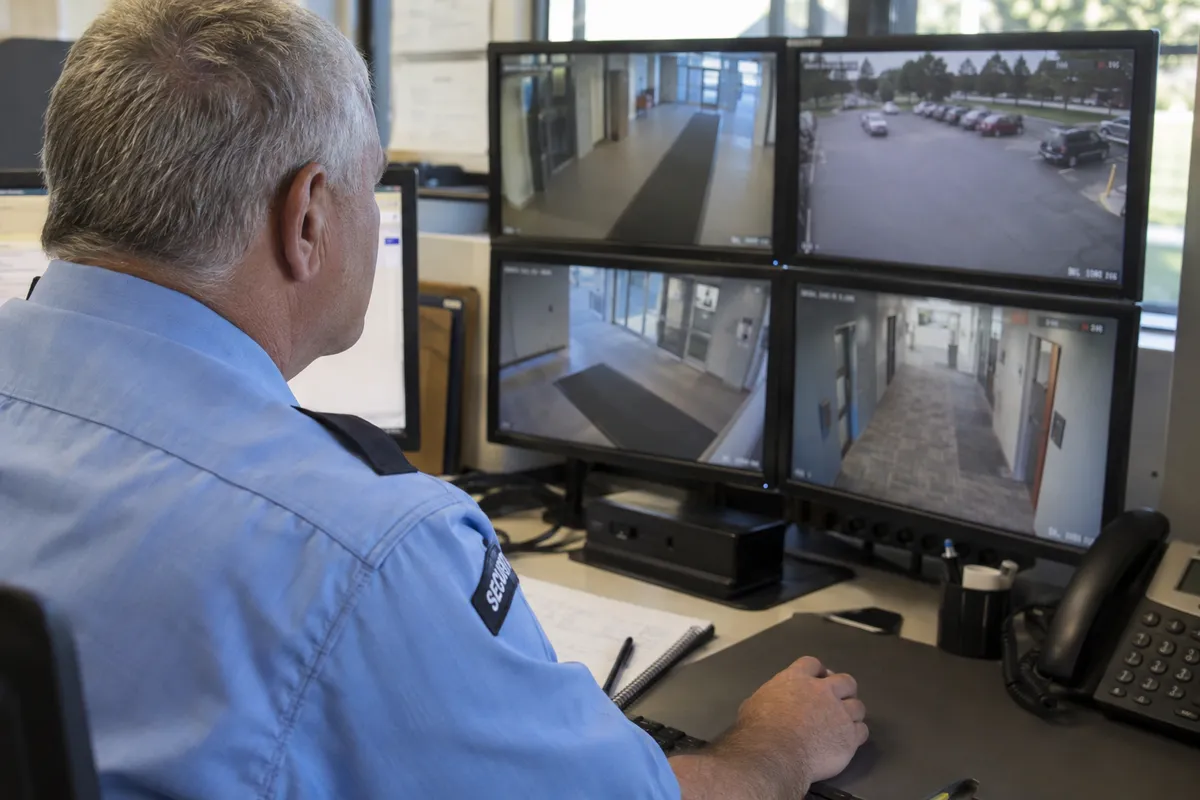 Illustrative private security work in Des Moines, Iowa: Mature male officer monitoring insurance-campus CCTV