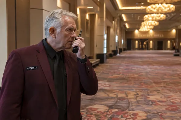 Illustrative private security work in Las Vegas, Nevada: Older male officer communicating by radio at convention venue