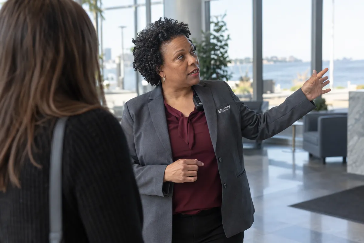 Illustrative private security work in Milwaukee, Wisconsin: Female officer explaining directions inside lakeside office lobby